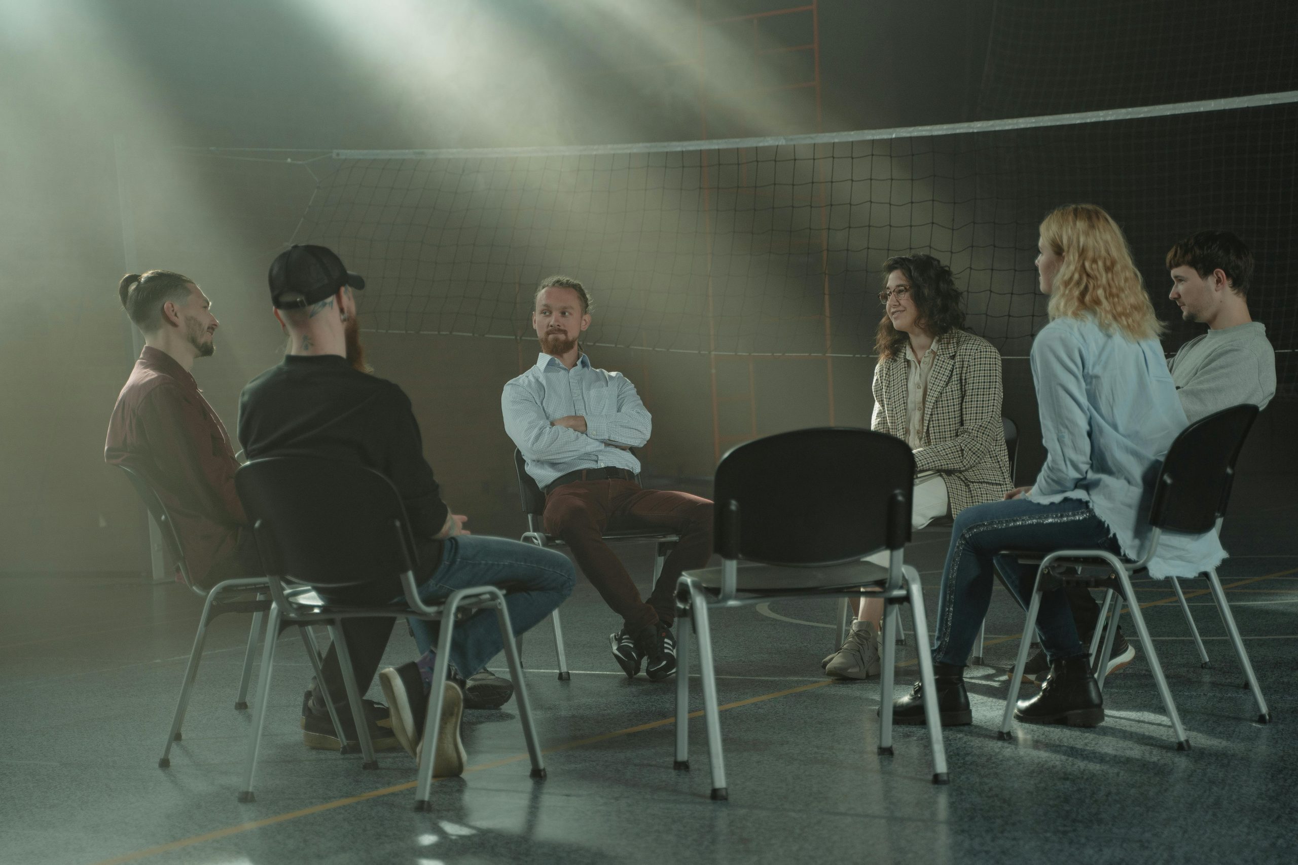Neue Wege A group therapy session with six adults seated in a circle, discussing support and mental health.